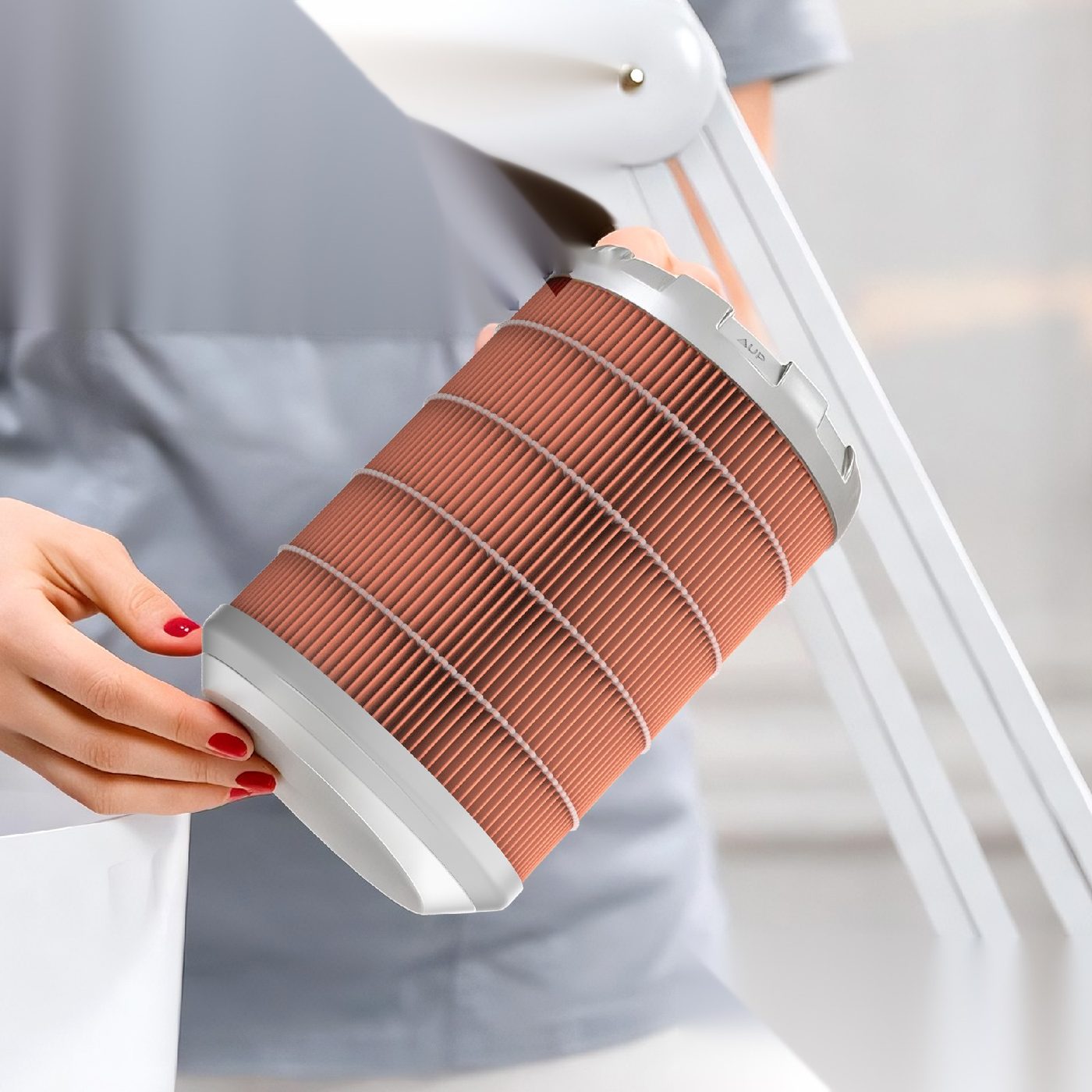 A nail technician holding a PureFibe cartridge filter beside a dust collector arm